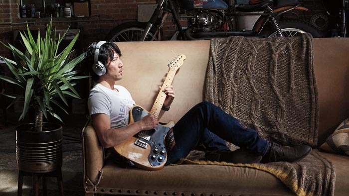 Image of QC35 on the man playing guitar on couch.