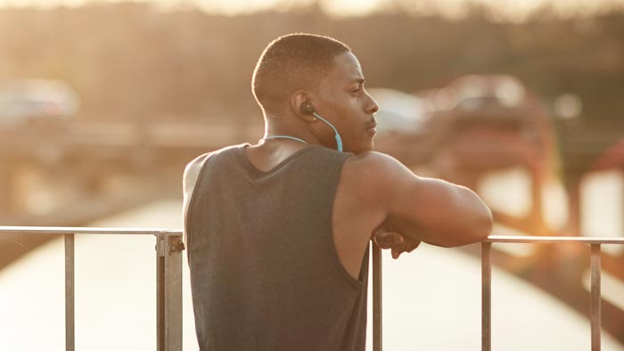 Image of SoundSport wireless worn by man resting on bridge.
