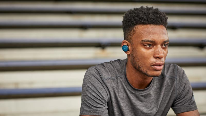 Image of a man sitting on stairs. Bose SoundSport Free wireless headphones.