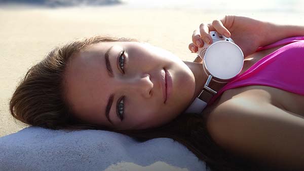 Girl wearing Cleer BT headphones sunning on beach